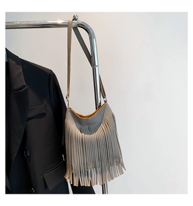 Detail of gray leather bag with long fringes and contrasting yellow interior lining