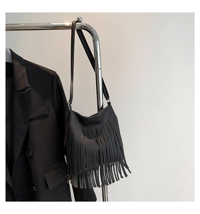 Detail showing the lychee texture leather and long fringe tassels on the black shoulder bag