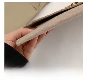 Detail shot of beige felt envelope bag featuring precision stitching and a gold metal lock