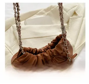 Detailed shot of brown bucket bag with chain strap and bow on office blazer