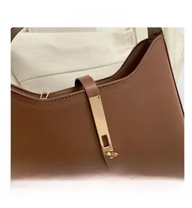 Detailed close-up of dark brown leather handbag featuring a golden metal twist lock and stitching