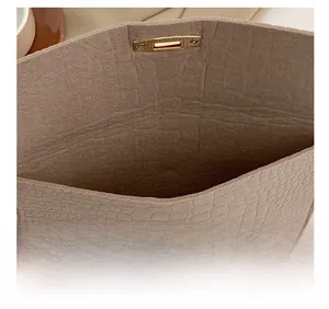 Detail view of beige stone-textured clutch bag interior with golden rotating lock