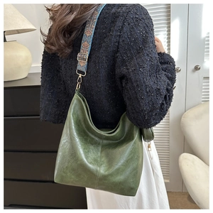 Detail of dark green hobo bag with ethnic style jacquard strap and matte gold buckle