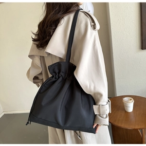 Chic black drawstring shoulder bag styled with a beige trench coat for a sleek look