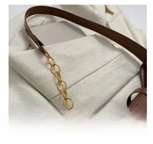 Macro detail of brown leather bag with elegant gold-tone oval metal chain links