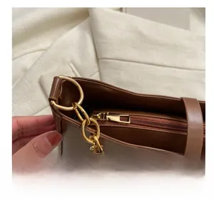 Detail of smooth metal zipper and gold hardware on brown leather shoulder bag
