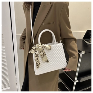 White quilted crossbody bag with stylish V-stitch pattern and decorative silk scarf detail