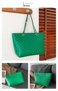 Detail of green quilted tote bag with golden chain strap and rhombus stitching texture