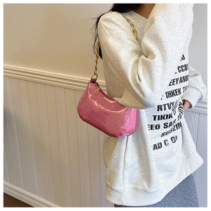 Dettaglio borsa baguette rosa glitterata con tracolla a catena dorata spessa