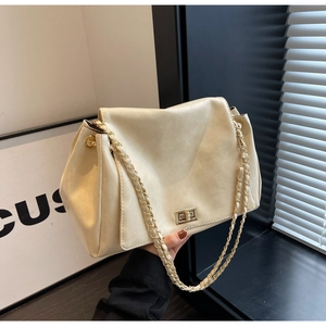Close-up of cream PU leather shoulder bag with gold chain strap and turn-lock buckle