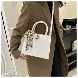 Sac à main blanc matelassé avec foulard en soie porté par un mannequin au bureau