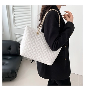 Quilted white shoulder bag with gold chain strap detail shown on model in minimal interior