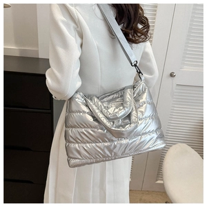 Detail view of the metallic silver puffer bag showing quilted texture and broad strap