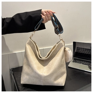 Detail of beige tote bag featuring ethnic jacquard strap and small round pendant pouch