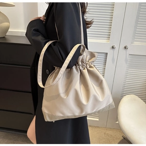 Detail of beige drawstring tote bag with smooth texture and fine stitching shoulder strap
