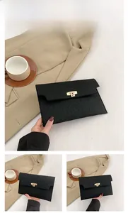 Detail of black envelope clutch with faux crocodile texture and golden metal clasp