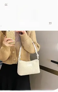Close-up of white corduroy shoulder bag with zipper closure and knot strap detail