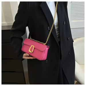 Detail of fuchsia leather crossbody bag with bold gold U-shaped buckle and chunky chain