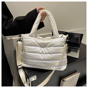 Detailed macro view of white quilted down tote bag with satin finish and metal hardware