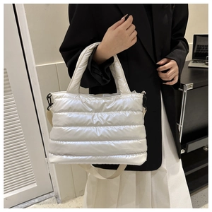 Detail of white quilted puffer bag featuring adjustable fabric shoulder strap and handle