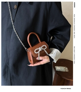 Close-up of a brown mini handbag with sparkling rhinestone bow and silver chain