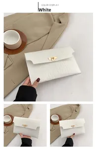 Detail of white crocodile embossed envelope clutch bag with gold rectangular twist lock