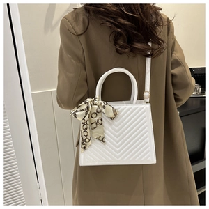 White quilted crossbody bag with silk scarf detail and gold hardware on model