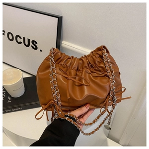 Detail of caramel pleated bucket bag featuring delicate bow ties and chain strap
