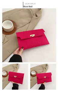 Close-up of rose red crocodile embossed envelope bag with gold twist lock on tabletop