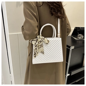 Détail d'un sac à main blanc matelassé avec un foulard décoratif et une bandoulière