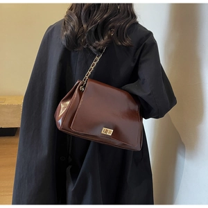 Side view of dark brown glossy leather shoulder bag with golden chain and square lock