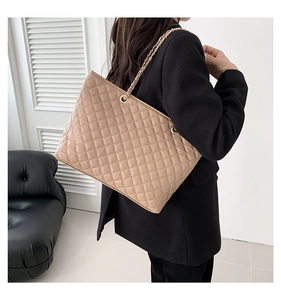 Detail of light beige quilted tote bag showing leather chain strap and diamond pattern