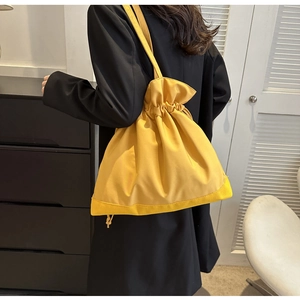Detail of yellow nylon bucket bag featuring a minimalist drawstring design and shoulder strap