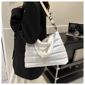 Detail view of white quilted puffy tote bag featuring adjustable nylon shoulder strap