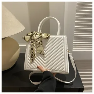 Détail du sac à main matelassé blanc avec poignée en foulard et surpiqûres en V