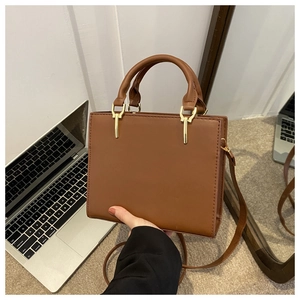 Close-up of brown leather handbag with golden hardware and adjustable shoulder strap
