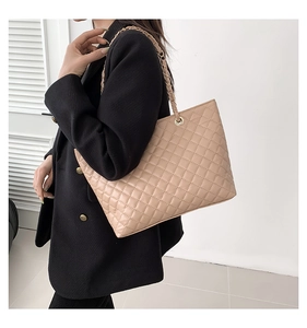 Close-up of quilted beige tote bag showing chain strap and fine faux leather texture