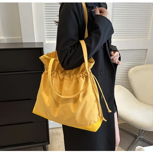 Detail view of a bright yellow drawstring tote bag featuring premium stitching and wide straps
