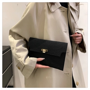 Detail of black crocodile embossed envelope clutch bag with gold turn-lock closure