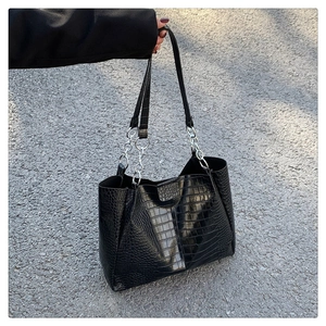 Detailansicht der schwarzen Tasche mit Krokodilprägung und silbernen Kettenriemen