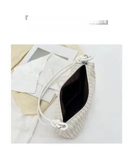 Detailed view of white corduroy shoulder bag with knotted strap and spacious dark lining