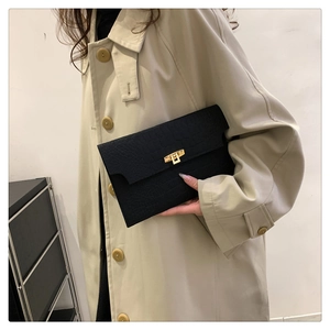 Close-up of black crocodile pattern leather envelope clutch with gold metal buckle