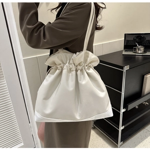 Detailed close-up showing the soft pleated drawstring closure and texture of the creamy white bag