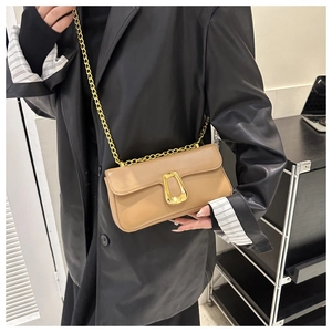 Detail of camel chain crossbody bag with gold horseshoe buckle on female model