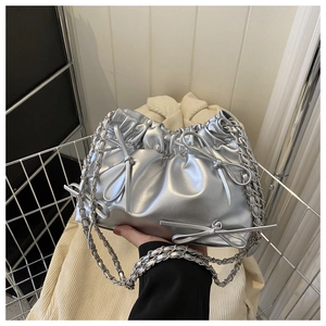 Detail of silver pleated bucket bag featuring a bow decoration and chain strap