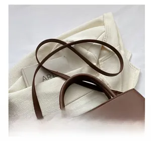 Detail of a brown leather tote bag with square quilting, long strap and gold metal buckle