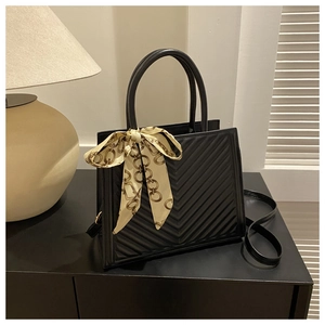 Sac à main noir matelassé avec texture en V et foulard décoratif en soie jaune sur l'anse