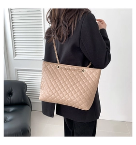 Vista posteriore di una modella con la borsa tote trapuntata beige e catena d'oro