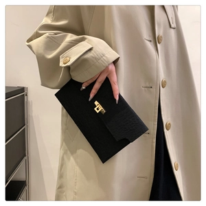 Detail of black crocodile pattern envelope clutch bag with gold metallic clasp