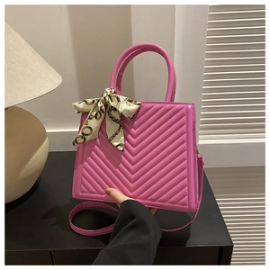 Détail du sac à main matelassé rose fuchsia avec foulard en soie et poignée ronde